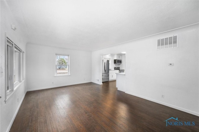 unfurnished living room featuring baseboards, visible vents, and dark wood finished floors