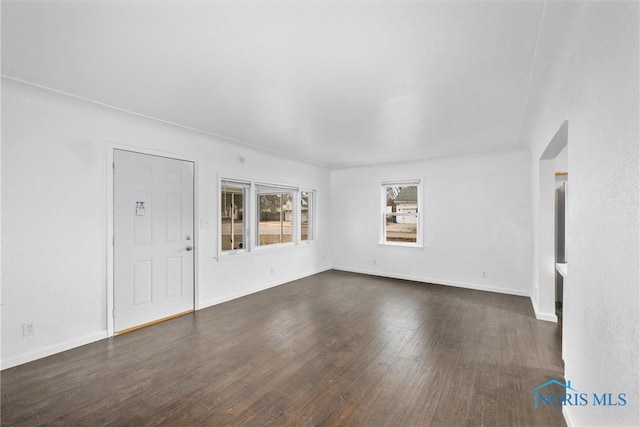 unfurnished living room featuring dark wood finished floors and baseboards