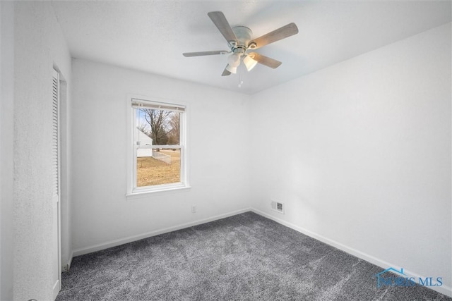 empty room with ceiling fan, visible vents, baseboards, and dark colored carpet