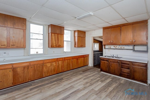 kitchen with brown cabinetry, light countertops, a sink, and wood finished floors