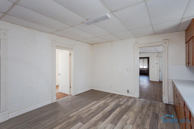 unfurnished room featuring a drop ceiling, baseboards, and wood finished floors