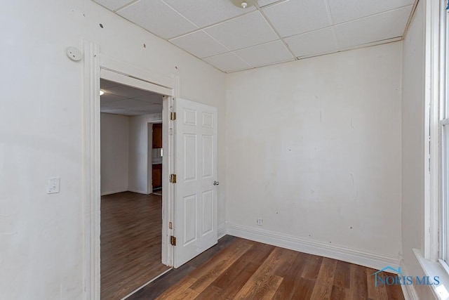 unfurnished room with dark wood-style floors, baseboards, and a drop ceiling