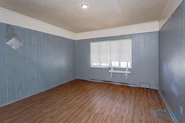 empty room featuring baseboard heating and wood finished floors