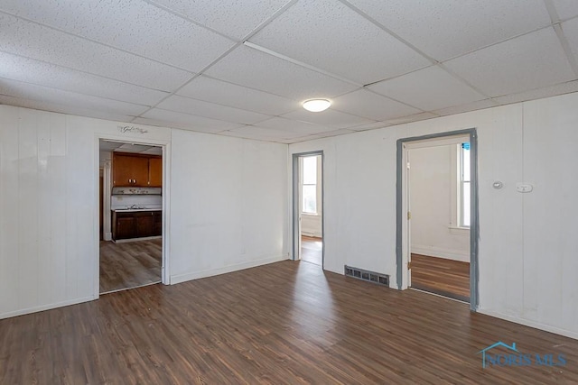 unfurnished room featuring a paneled ceiling, baseboards, visible vents, and wood finished floors