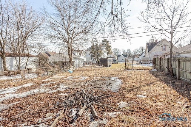 view of yard featuring a residential view, fence, an outdoor structure, and a storage unit