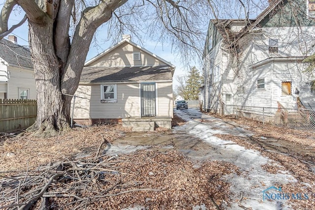 back of house with fence and a chimney