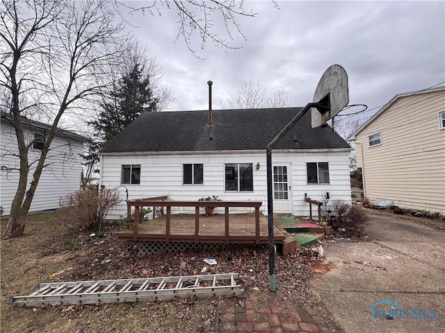 rear view of property featuring a shingled roof and a deck