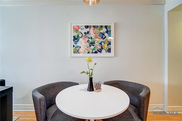 dining space featuring ornamental molding, light wood-style flooring, and baseboards