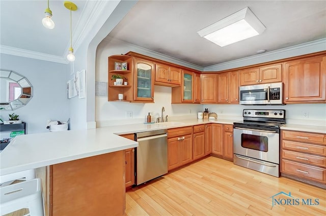 kitchen with a peninsula, stainless steel appliances, crown molding, light wood-style floors, and a sink