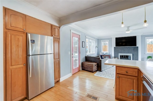 kitchen featuring visible vents, appliances with stainless steel finishes, a glass covered fireplace, light wood-style floors, and plenty of natural light