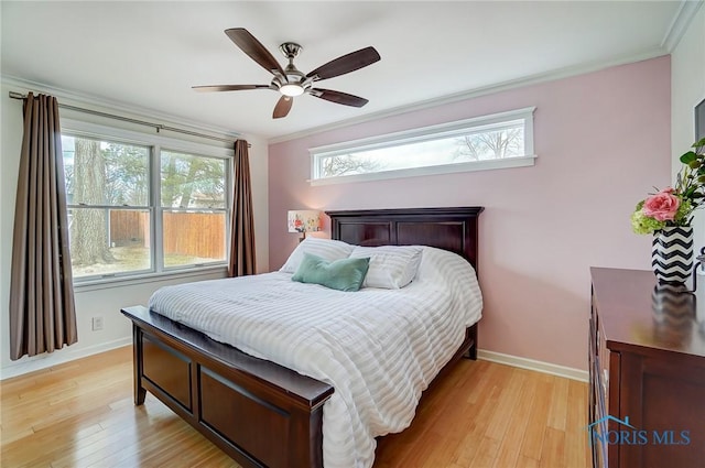 bedroom featuring light wood finished floors, multiple windows, and baseboards