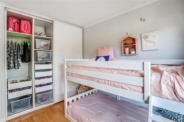 bedroom with a closet, crown molding, and wood finished floors