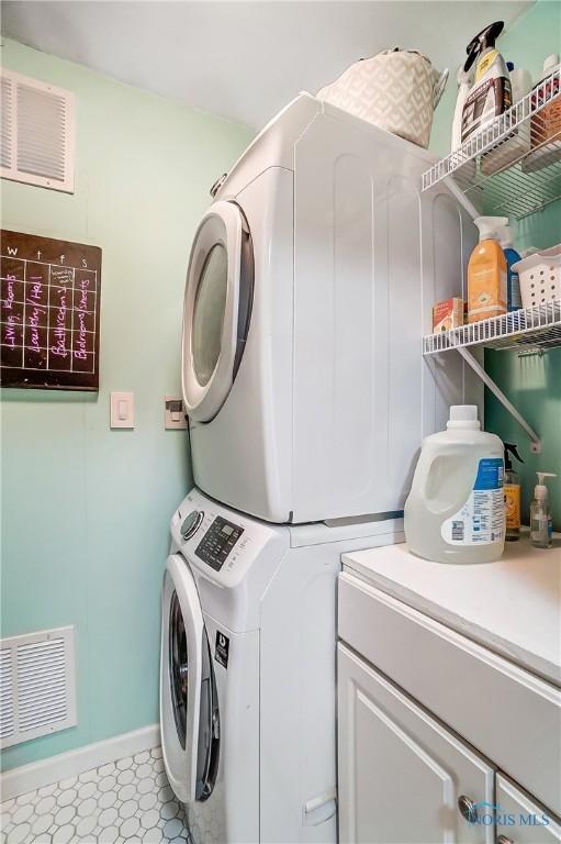 washroom featuring laundry area, baseboards, visible vents, and stacked washer / drying machine