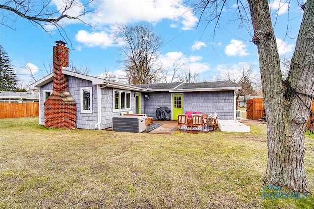 rear view of property featuring a deck, a yard, a chimney, and fence