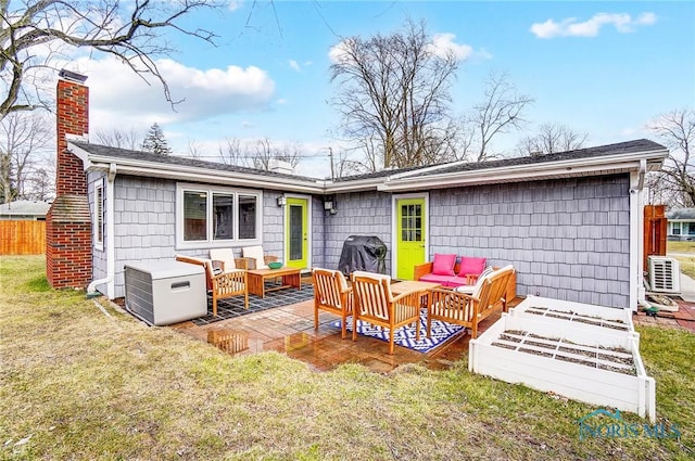 back of house featuring fence, an outdoor living space, a lawn, a chimney, and a patio area