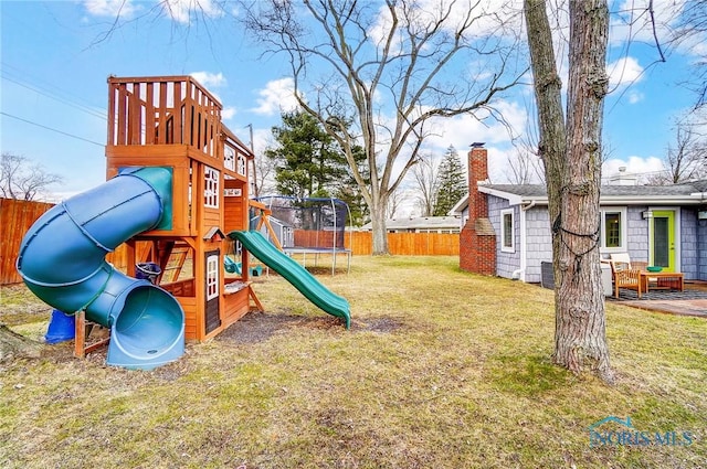 view of jungle gym with a trampoline, fence, and a lawn