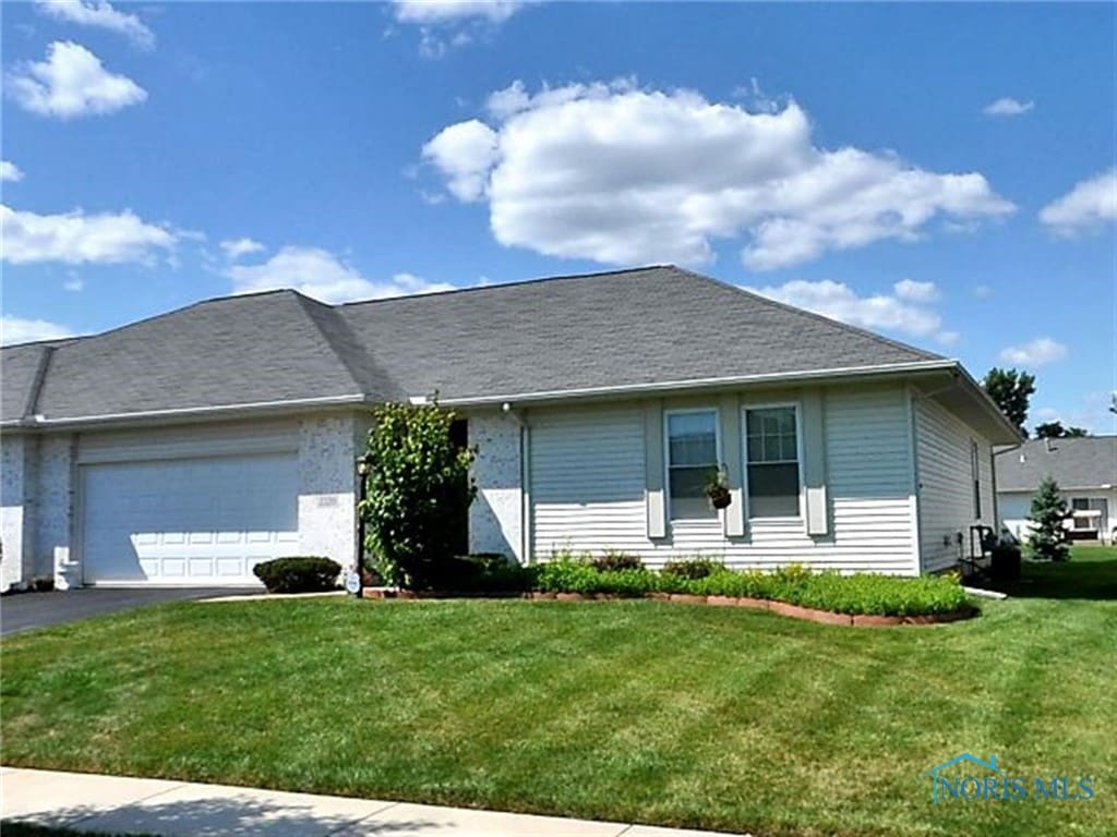 ranch-style home featuring driveway, a front lawn, and an attached garage