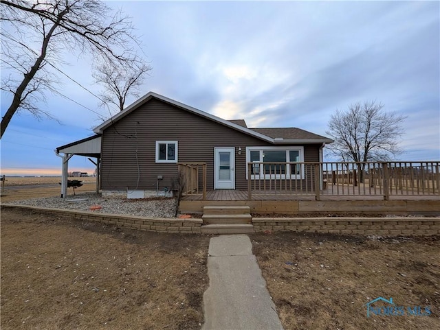 view of front of home featuring a deck and roof with shingles