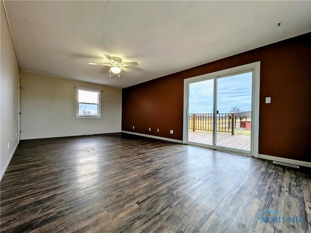 spare room featuring a ceiling fan, dark wood finished floors, and baseboards