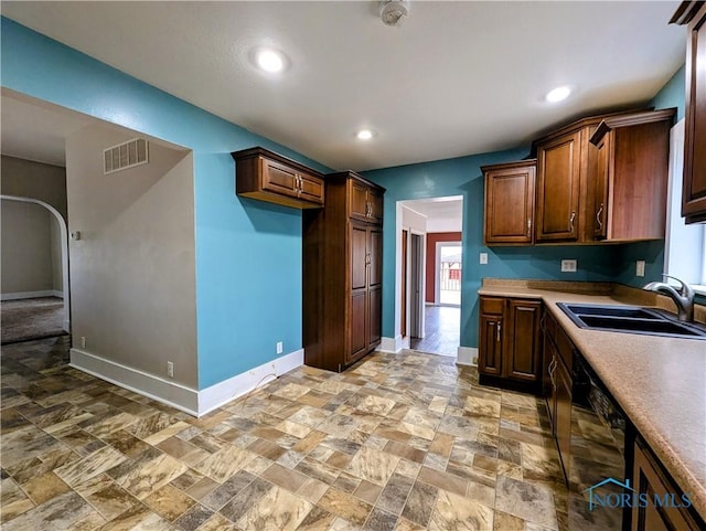 kitchen featuring dishwasher, a sink, visible vents, and baseboards