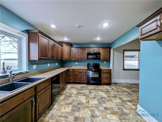 kitchen with black appliances, plenty of natural light, a sink, and light countertops