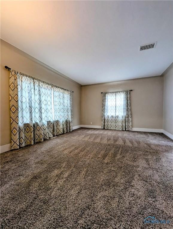 carpeted empty room featuring baseboards and visible vents