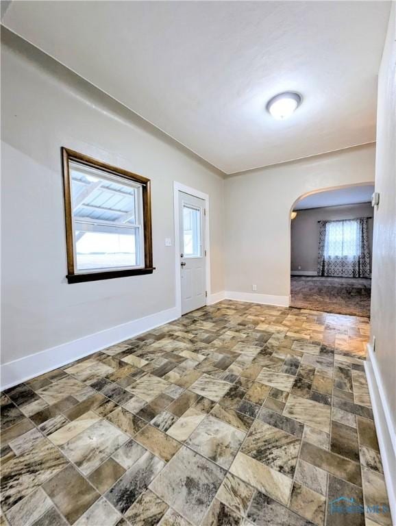 empty room with baseboards and arched walkways