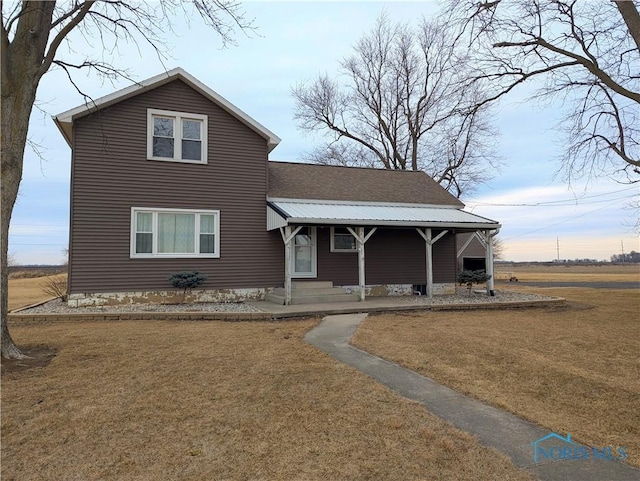 traditional home with entry steps, metal roof, and a front lawn