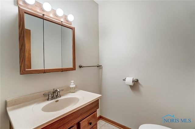 bathroom with tile patterned flooring, baseboards, vanity, and toilet