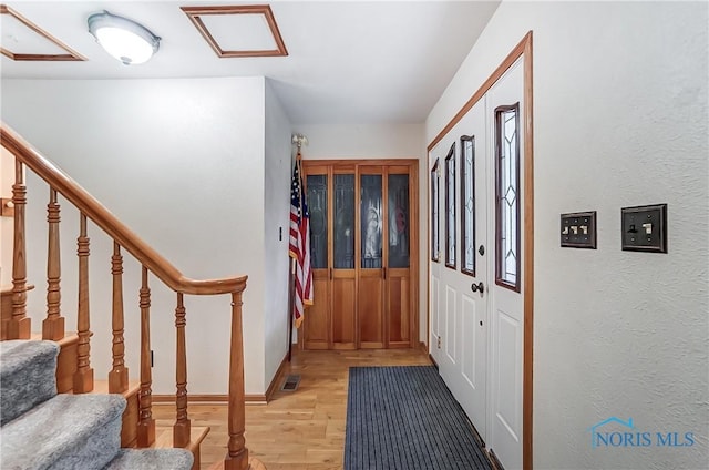 foyer entrance with light wood-type flooring, baseboards, stairs, and visible vents