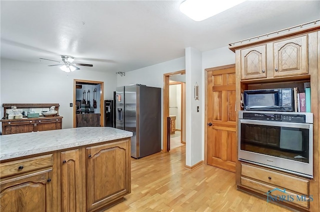 kitchen featuring light wood-style flooring, appliances with stainless steel finishes, light countertops, and a ceiling fan