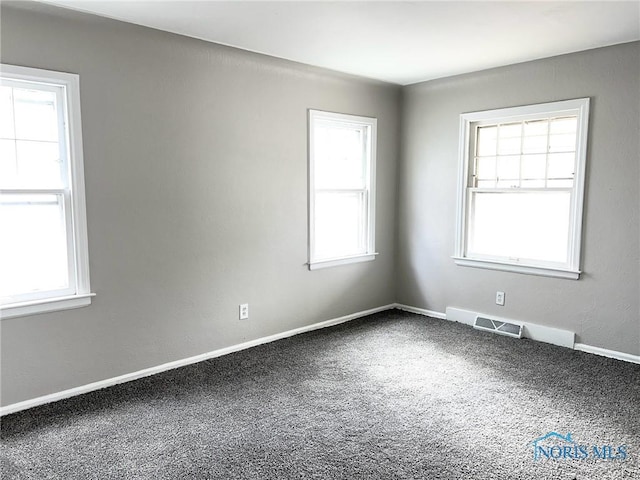 carpeted empty room with baseboards, visible vents, and a wealth of natural light