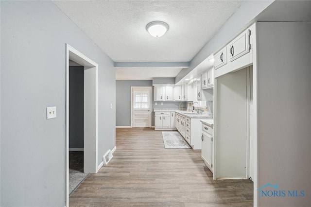 kitchen featuring visible vents, light countertops, light wood-type flooring, and white cabinetry