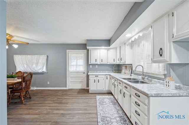 kitchen featuring a textured ceiling, wood finished floors, a sink, white cabinetry, and light countertops