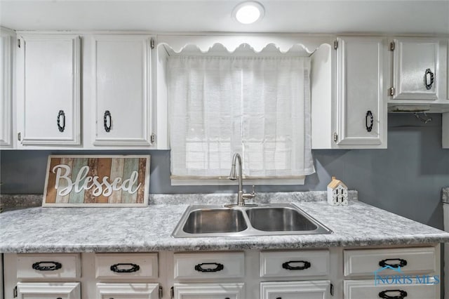 kitchen with light countertops, white cabinets, and a sink