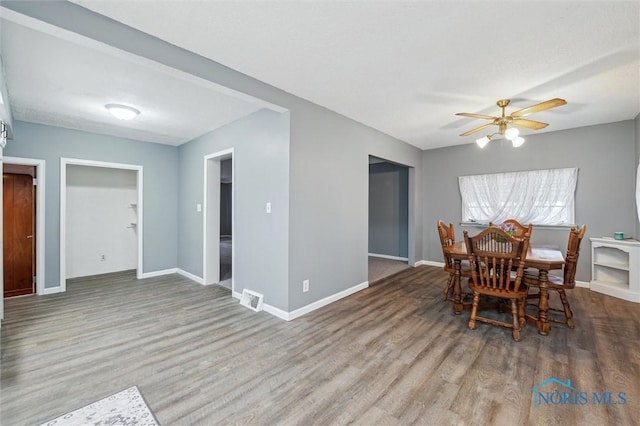 dining space with a ceiling fan, visible vents, baseboards, and wood finished floors