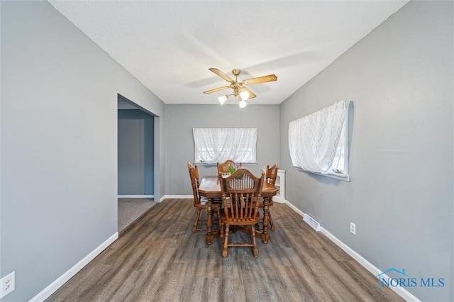 dining space featuring visible vents, a ceiling fan, a textured ceiling, wood finished floors, and baseboards