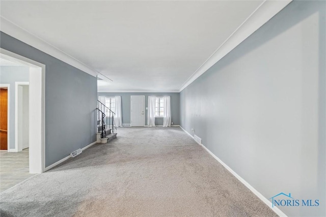 unfurnished room with carpet flooring, visible vents, baseboards, stairs, and ornamental molding