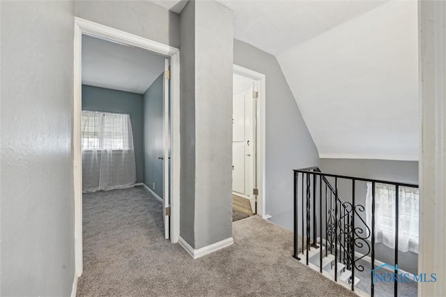 hallway featuring lofted ceiling, carpet flooring, an upstairs landing, and baseboards