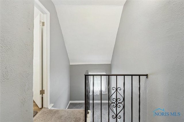 stairs featuring vaulted ceiling, a textured wall, carpet floors, and baseboards