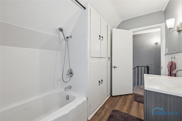 full bathroom featuring  shower combination, lofted ceiling, vanity, and wood finished floors