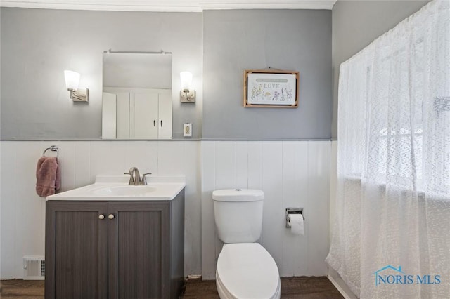 bathroom featuring visible vents, wainscoting, vanity, and toilet