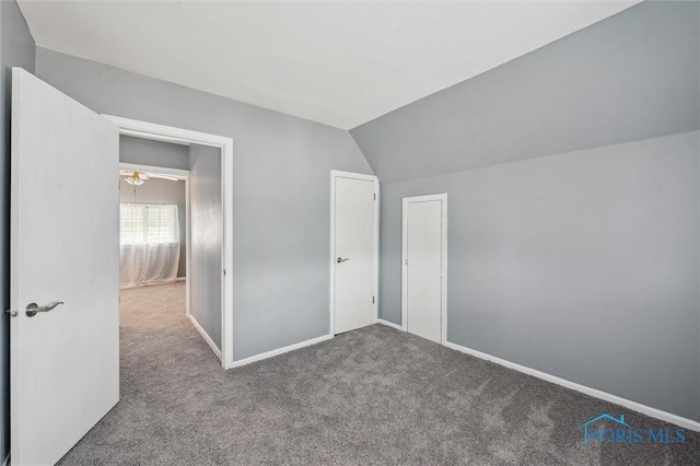 unfurnished bedroom featuring carpet floors, baseboards, and lofted ceiling