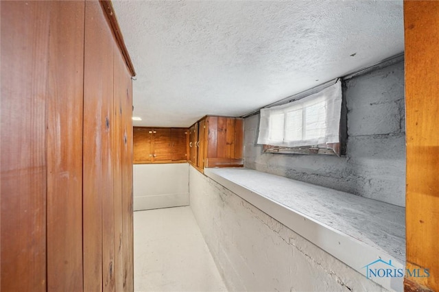 corridor with a textured ceiling and finished concrete flooring