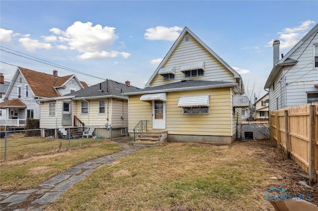 rear view of house with entry steps, central air condition unit, fence, and a lawn