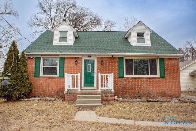 view of front facade featuring brick siding and a shingled roof