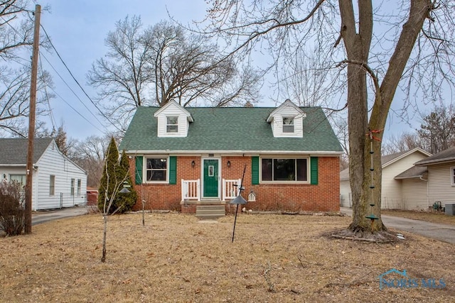 new england style home with a shingled roof and brick siding