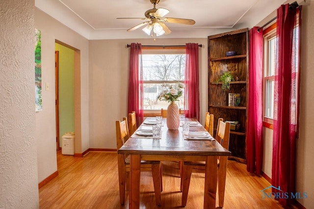 dining area featuring baseboards, ceiling fan, and light wood-style floors