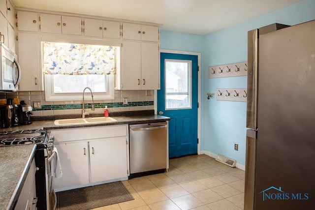 kitchen featuring stainless steel appliances, a healthy amount of sunlight, a sink, and backsplash