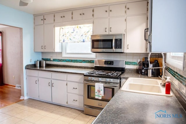 kitchen featuring tasteful backsplash, appliances with stainless steel finishes, white cabinets, and a sink